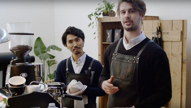 Two baristas behind coffee machines