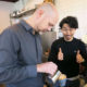 Man making thumbs up sign watching milk being poured into coffee