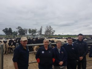 Farmers leaned against gate with cows in background