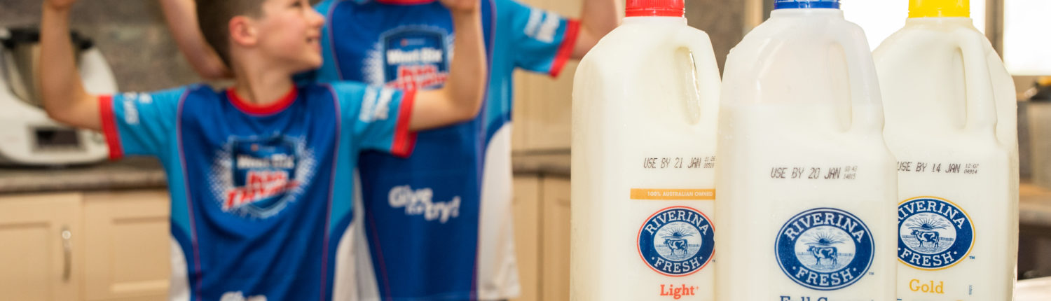 Two boys smiling and flexing muscles behind Riverina Fresh milk